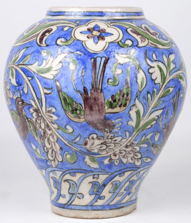 Een vaas van Perzisch aardewerk met een meerkleurig decor van vogels en druiven.