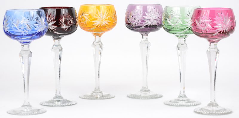 Een reeks van zes glazen van geslepen kristal in verschillende kleuren.