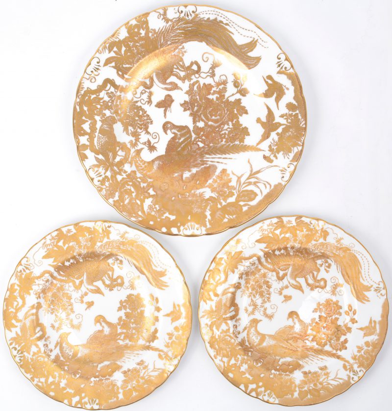 Een groot en twee kleine borden van porselein, versierd met een verguld decor van vogels.