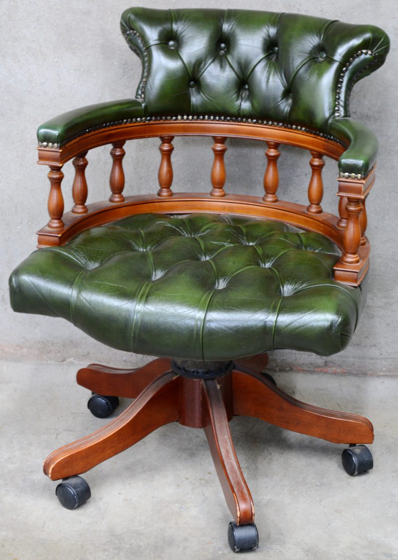 Een bureaustoel met gedraaide spijltjes, bekleed met gecapitonneerd groen leder. Op wielen.