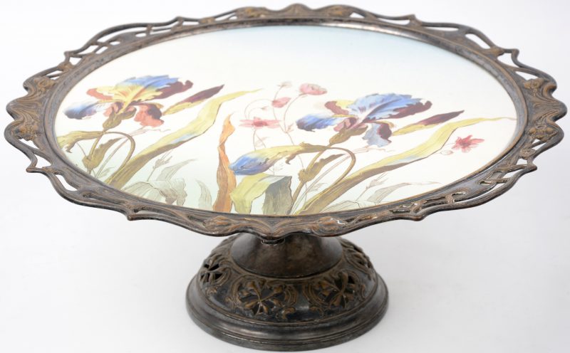 Een art nouveau tazza van verzilverd metaal en porselein, versierd met een meerkleurig decor van bleoemen.