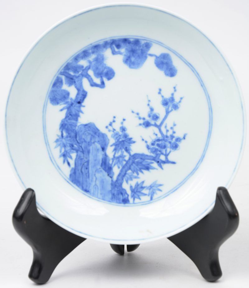 Een schoteltje van Chinees porselein met een blauw op wit plantendecor. Onderaan gemerkt.