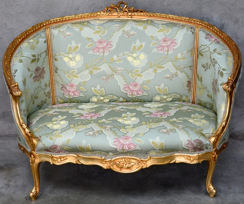 Een zitbank van gesculpteerd en goudgepatineerd hout in Lodewijk XV-stijl.