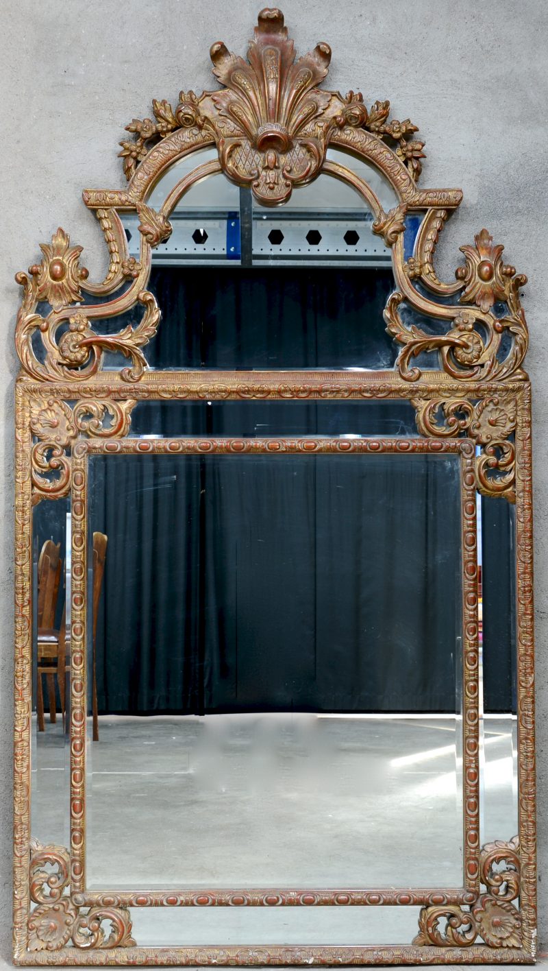Een spiegel van verguld hout in barokke stijl.