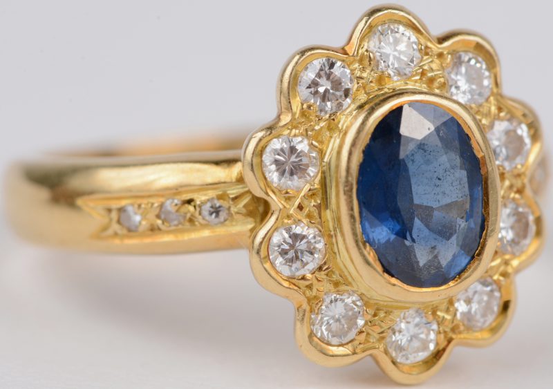 Een 18 karaats geel gouden ring bezet met diamanten met een gezamenlijk gewicht van ± 0,50 ct. en een centrale saffier van ± 1 ct.