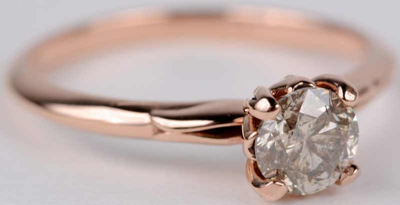 Een 14 karaats roze gouden ring bezet met een Fancy color diamant van 0,71 ct. SI1. en kleine briljantjes.