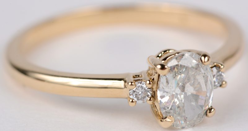 Een 14 karaats geel gouden ring bezet met een diamant van 0,56 ct. SI2. Color E. en twee kleine briljantjes.