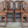 Een Chinese tafel met vier bijpassende stoelen van gesculpteerd tropisch hout.