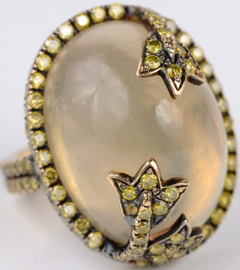 Een 18 karaats gepatineerde gouden ring bezet met een gele diamanten met een gezamenlijk gewicht van ± 1,28 ct. en een maansteen van ± 10 ct.