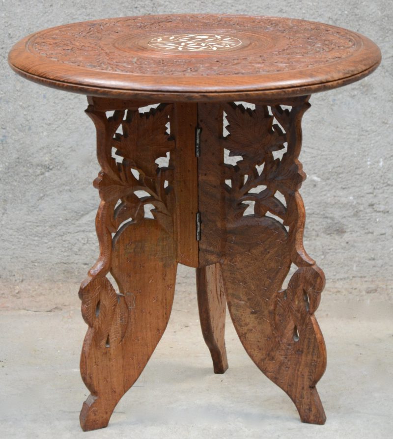 Een houten tafeltje met rond afneembaar blad opvouwbare driepoot met een gesculpteerd decor van bloemen en vogels en afgewerkt met ingelegd ivoor.