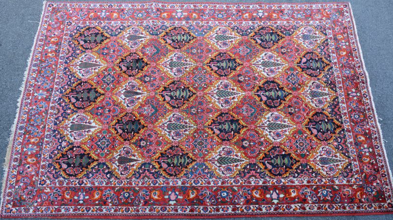 Een handgeknoopt Perzisch wollen tapijt met een decor van bomen.