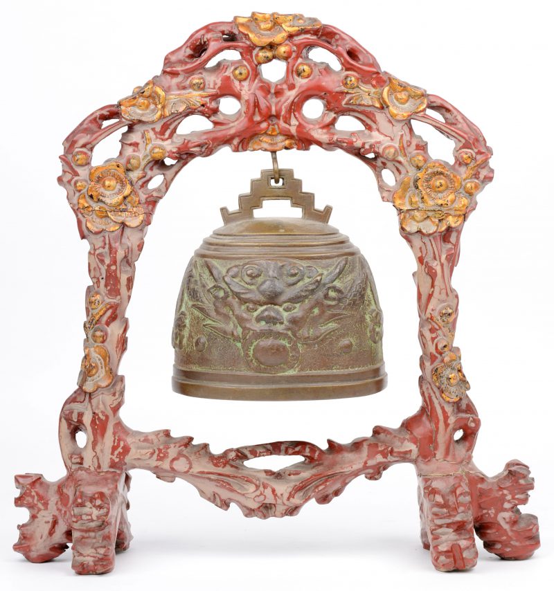 Een Chinese bel in een opengewerkte staander van rood- en goudgepatineerd hout.