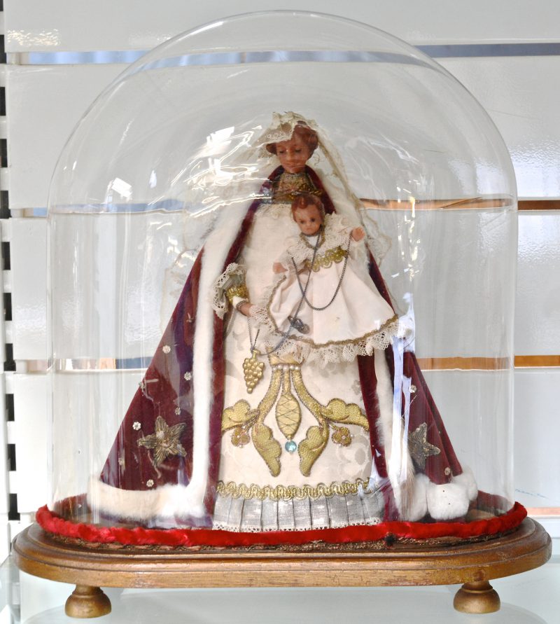 Een wassen Madonna met kind onder glazen stolp.