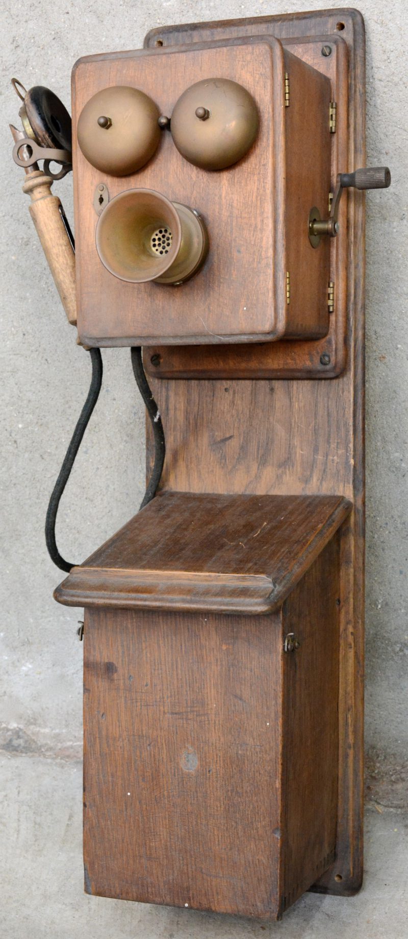 Een oude wandtelefoon in houten kast. Hoorn niet origineel.