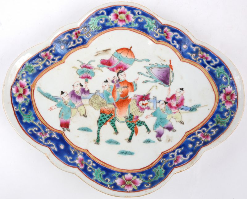 Een schaal op voet van Chinees porselein met een meerkleurog decor van personages op een fabeldier en met vaandels. Onderaan gemerkt.
