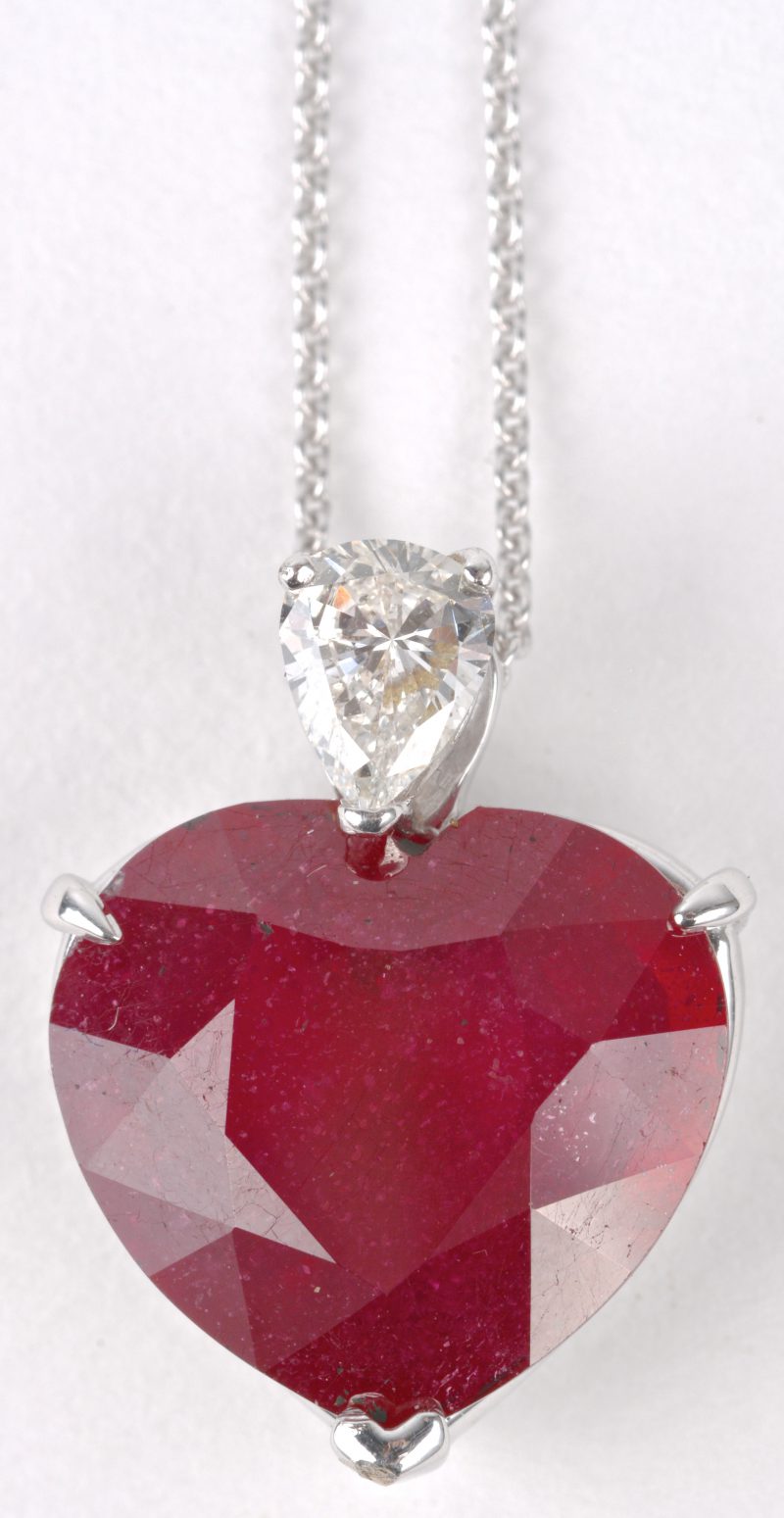Een 18 karaats wit gouden ketting met hanger bezet met een hartvormige robijn van ± 8 ct. en een druppelvormige diamant van ± 0,40 ct.