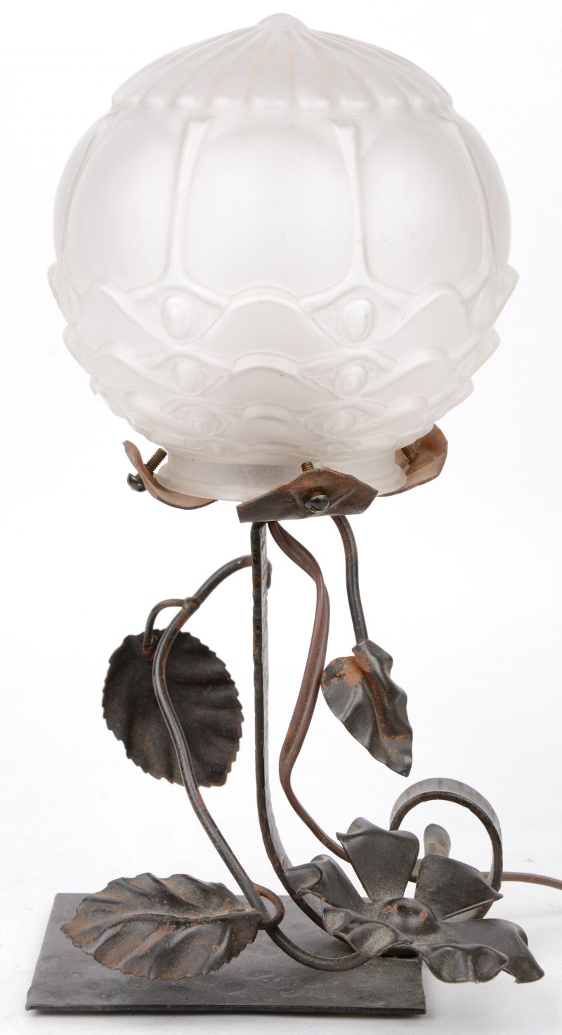 Een art deco lampje van smeedijzer met een bolle glazen lampenkap.