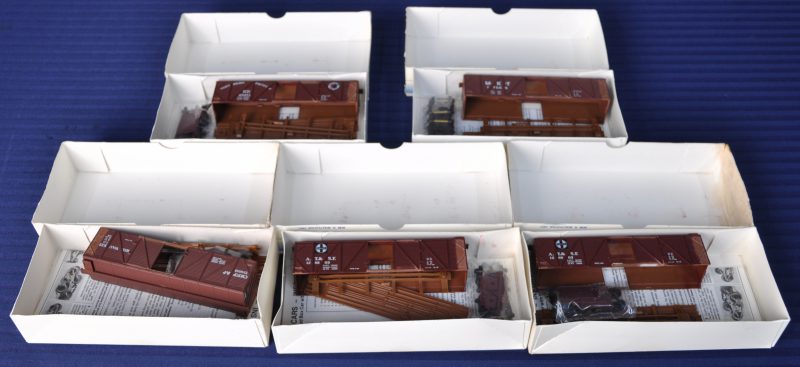 Vier gesloten houten goederenwagons van verschillende Amerikaanse maatschappijen. Spoortype HO. Als bouwpaketten. In originele dozen.