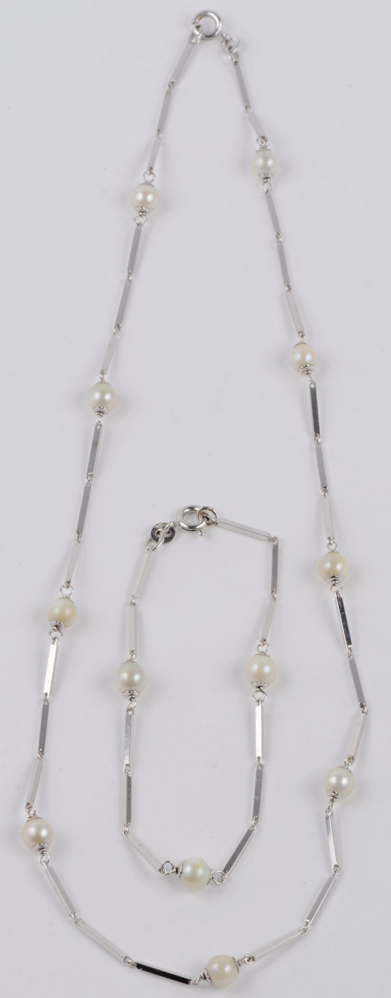 Een 18 karaats wit gouden halssnoer met bijpassende armband bezet met parels.