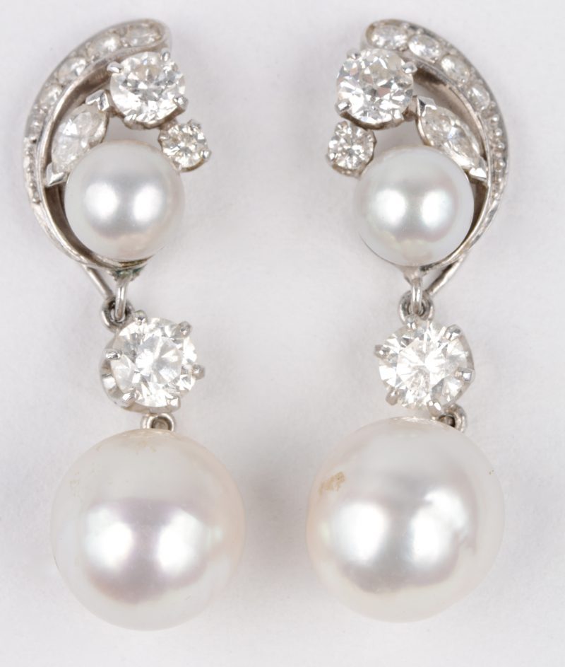 Een paar 18 karaats wit gouden oorbellen bezet met diamanten met een gezamenlijk gewicht van ± 1,40 ct. en vier grijze parels.