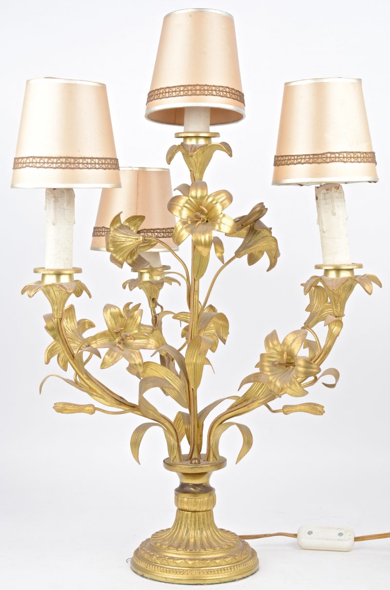 Een koperen lamp met vier lichtpunten in de vorm van bloemen.