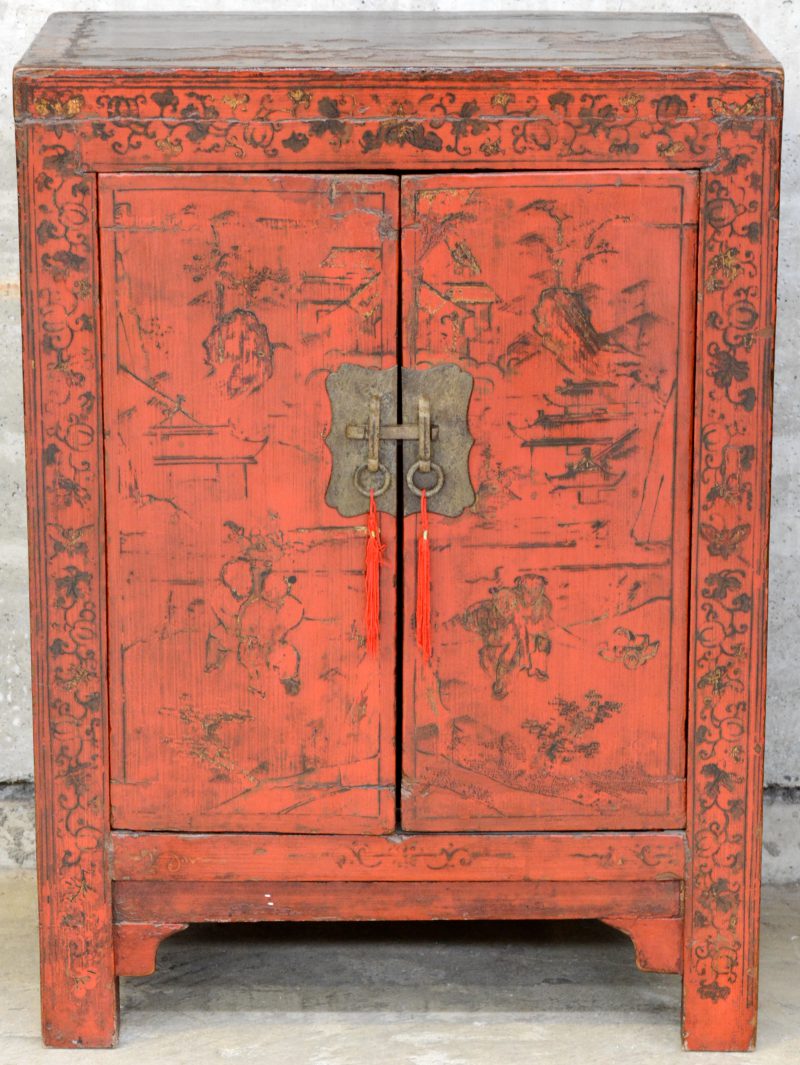 Een rood gelakt Chinees kastje met twee deuren.