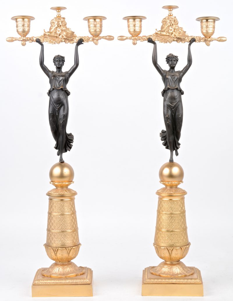 Een paar bronzen vergulde kandelaars in empirestijl, gedragen door bronzen vrouwen.