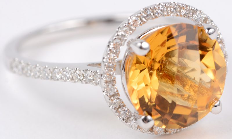 Een 18 karaats wit gouden ring bezet met diamanten met een gezamenlijk gewicht van ± 0,40 ct. en een centrale citrine van ± 3,50 ct.