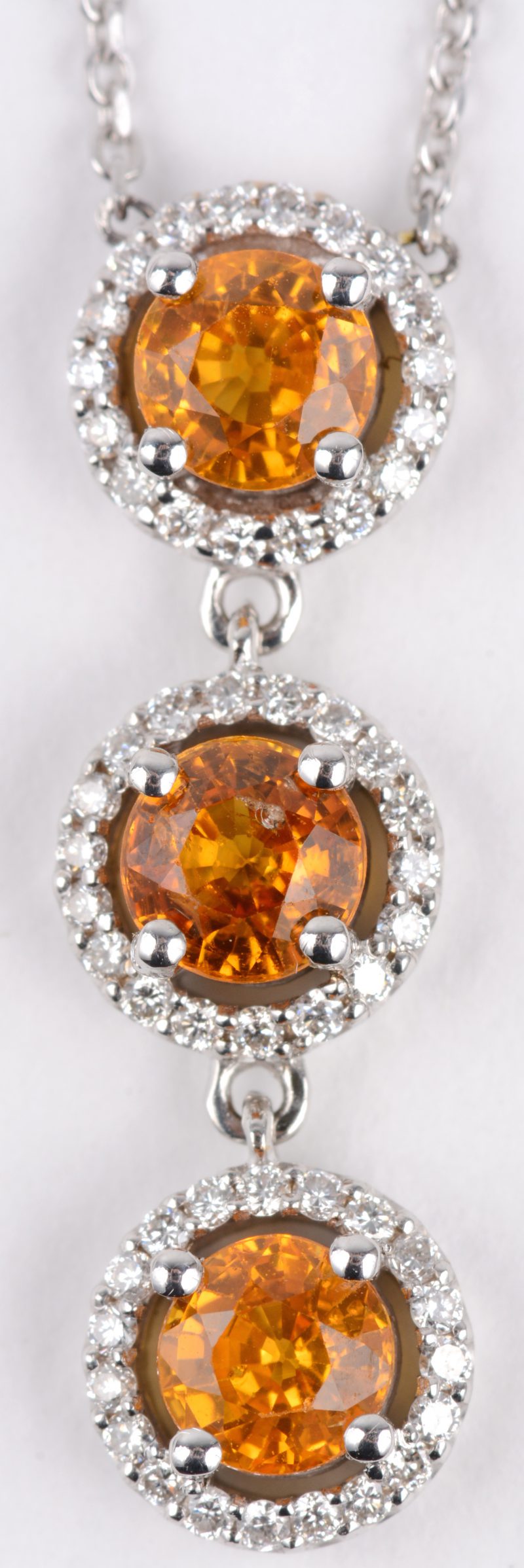 Een 18 karaats wit gouden ketting met hanger bezet met diamanten met een gezamenlijk gewicht van ± 0,50 ct. en drie gele saffieren met een gezamenlijk gewicht van ± 1,20 ct.