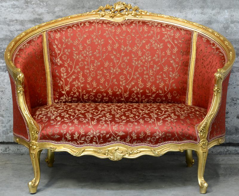 Een zitbank van gesculpteerd en goudgepatineerd hout in Lodewijk XV-stijl.