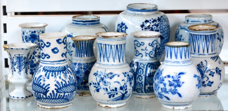 Een lot vazen: Drie dekselvaasjes (zonder deksels), zeven buikvaasjes en een hoornvaasje van Delfts aardewerk met blauw op witte decors. XVIIIe en XIXe eeuw. Verscheidene met randschade.