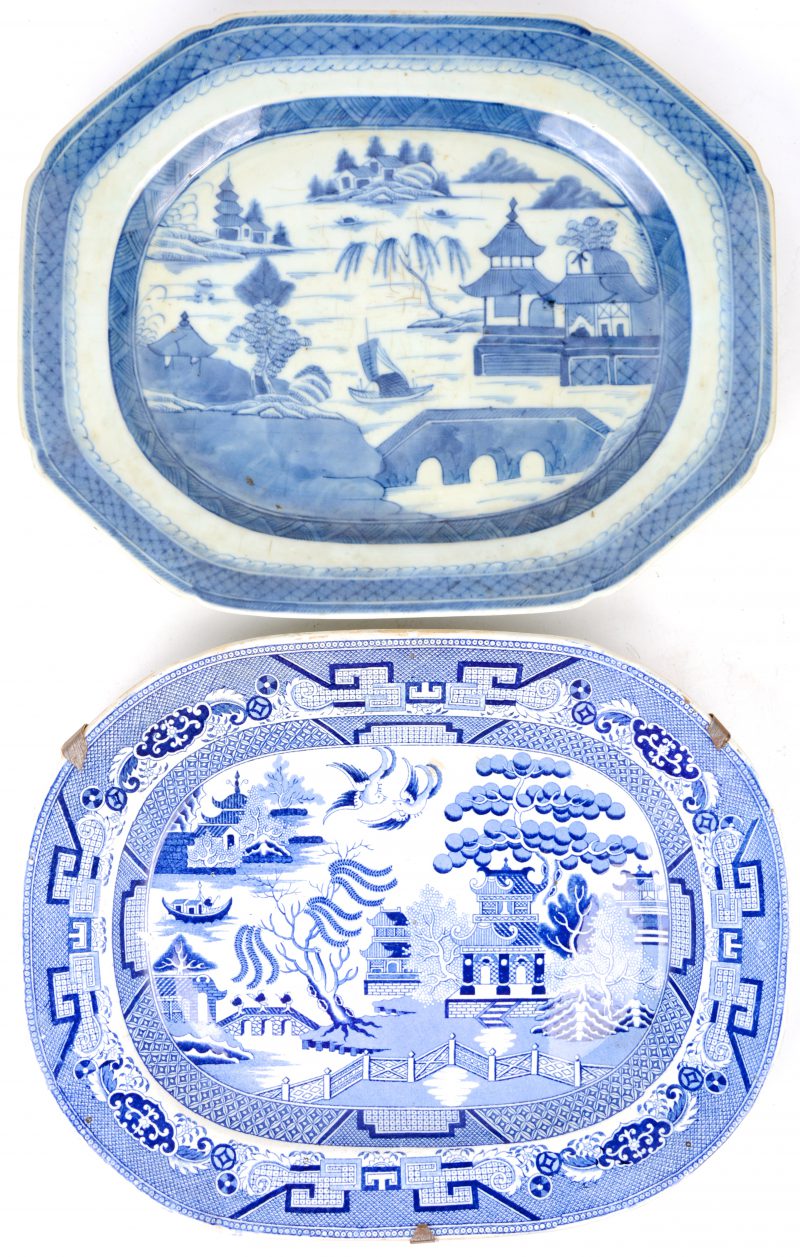 Twee schotels met blauw op witte landschapdecors, waarbij één Chinese van porselein en één Engelse van aardewerk.