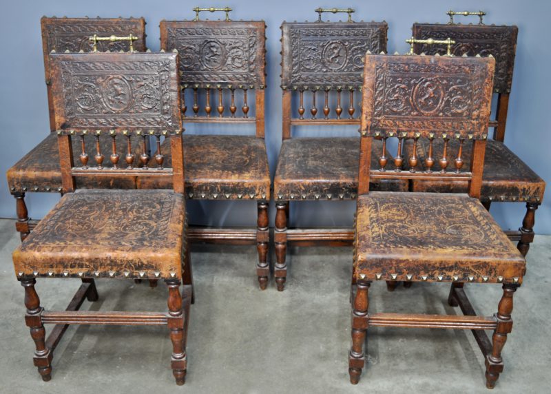 Een reeks van zes stoelen met gedreven lederen zit en rug en met balustervormige spijltjes en messingen handvatten. (Eén handvat manco)