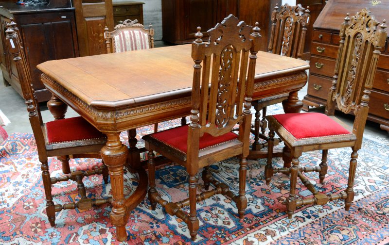 Een gebeeldhouwd eikenhouten tafel in renaissancestijl met vier bijpassende stoelen, bekleed met rood fluweel. Twee ruggen beschadigd. We voegen er een stoel in Lodewijk XVI-stijl aan toe.