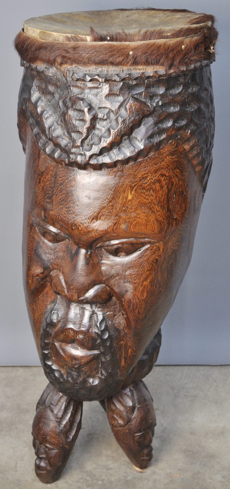 Een Afrikaanse tamtam van gebeeldhouwd hardhout in de vorm van een mannenhoofd.