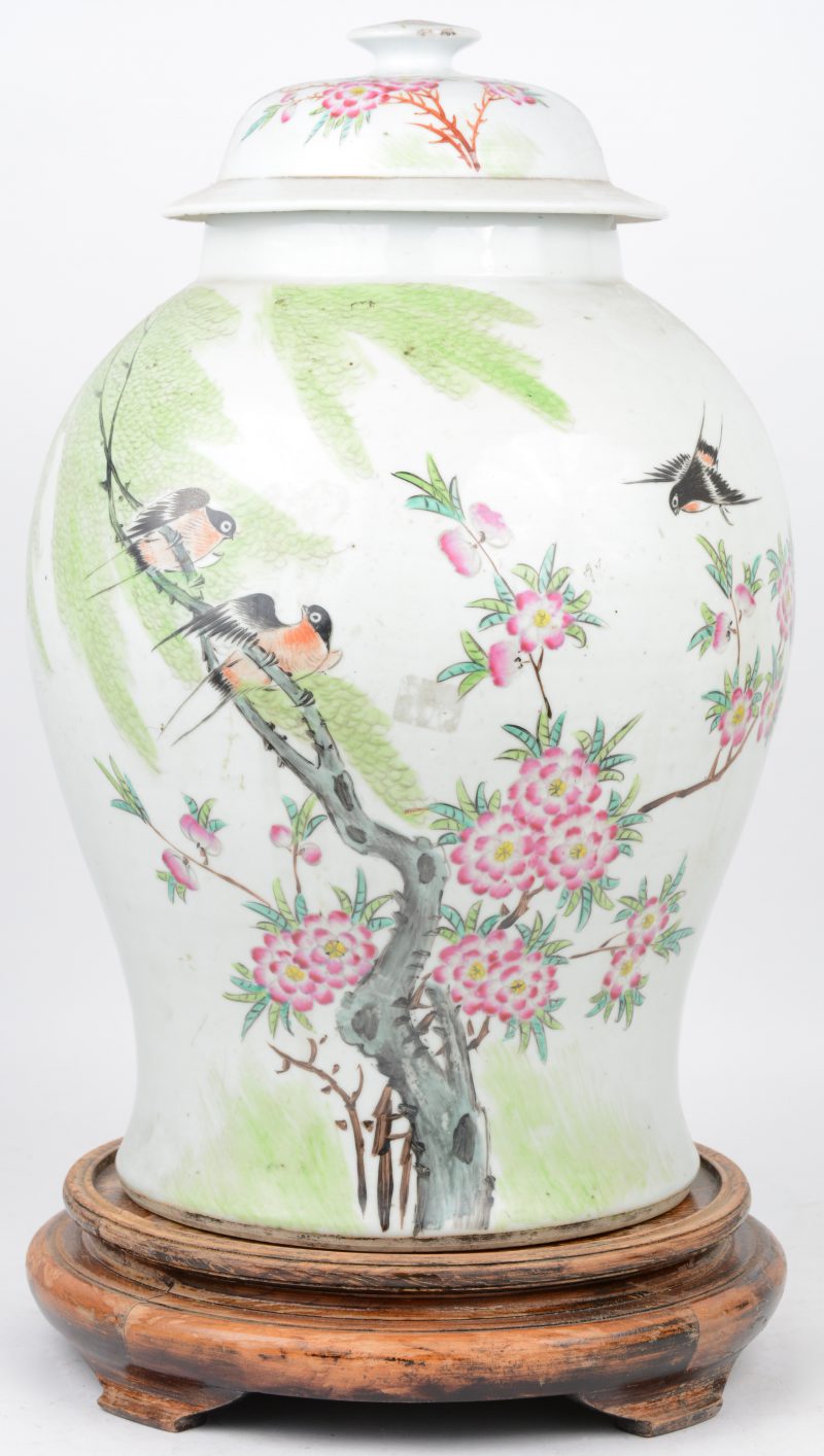 Een dekselvaas van Chinees polychroom porselein met pleine page decor van vogels en bloeiende struiken. Randschade aan de dekselknop. Onderaan gemerkt. Met houten sokkel.