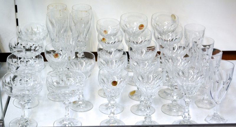 Een gedeelte glasservies van geslepen kristal in Louis-Philippe-stijl gemerkt met label. Bevat: 5 coupes, 6 waterglazen, 5 rode wijn glazen, 6 witte wijn glazen, 5 fluiten. We voegen er 5 fluiten met een ander, getorste motief aan toe. 31 stuks.