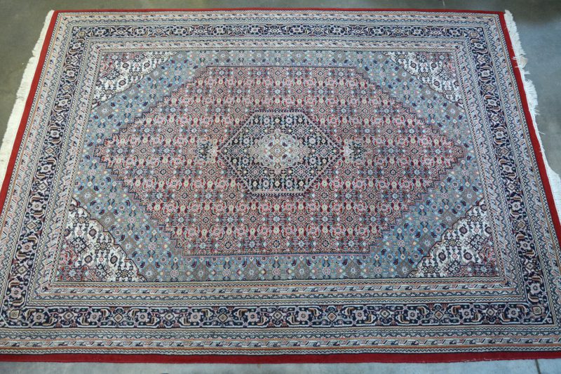 Een handgeknoopt Indisch wollen tapijt met een geometrisch motief.