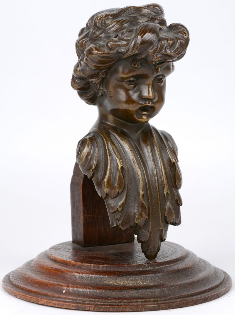 “Kinderkopje”. Een bronzen ornament op houten sokkel.