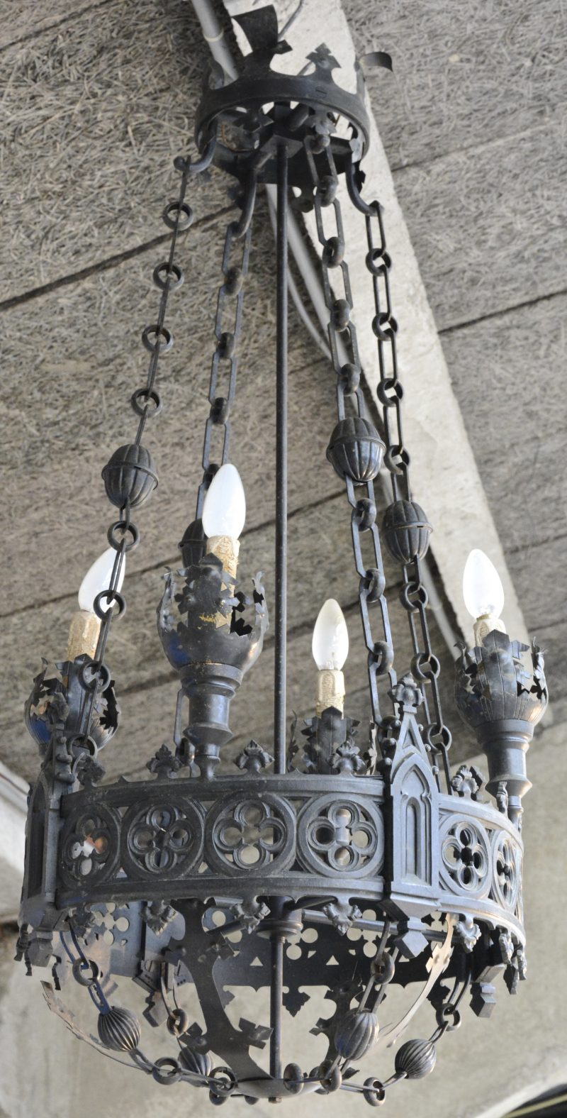 Een smeedijzeren luchter in gotische stijl met vier lichtpunten.