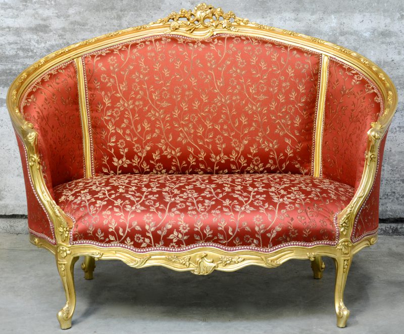 Een zitbank van gesculpteerd en goud gepatineerd hout in Lodewijk XV-stijl.
