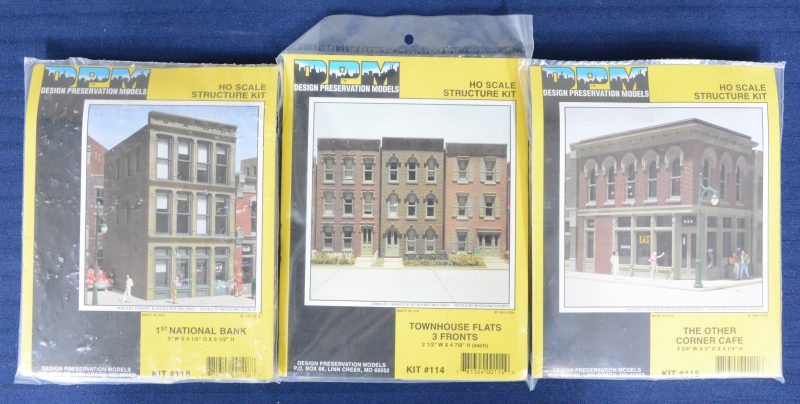 Drie modelbouwpakketten op schaal HO:- “Townhouses flats. 3 fronts”.- “The Other Corner Cafe”.- “1st National Bank”. Compleet en in originele verpakkingen.