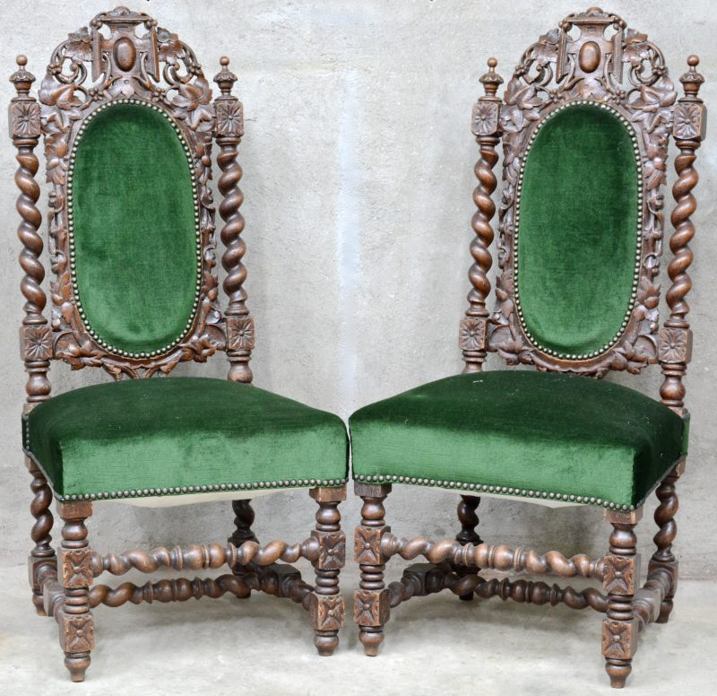 Een paar gebeeldhouten stoelen met groen fluweel.