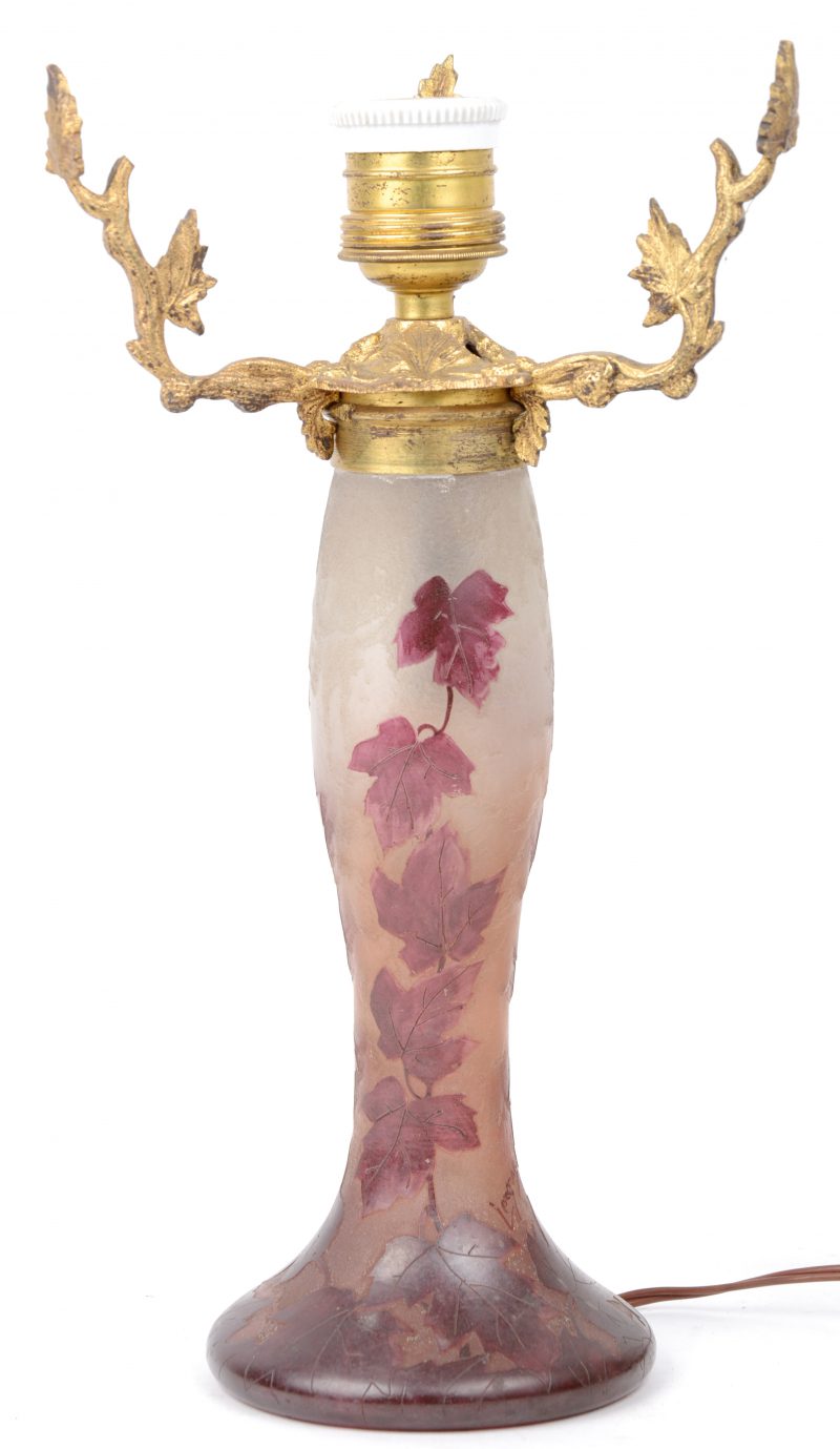 Een glazen lampvoet van met een gegraveerd bladerdecor met messingen mantuur. Kap manco. Gesigneerd ‘Legros’.