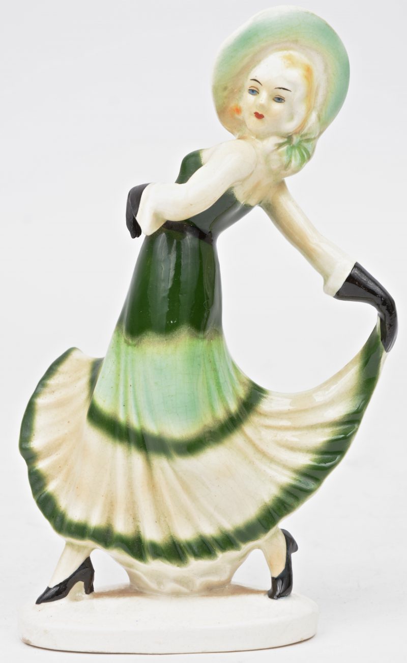 Een porseleinen Art - Deco beeldje van een paraderende vrouw met hoed.