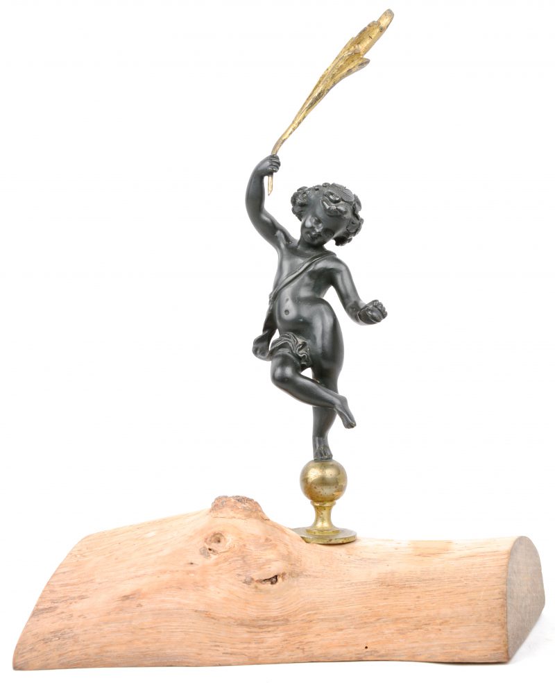 een bronzen putto met palmtak. Gemonteerd op een houten voetstuk.