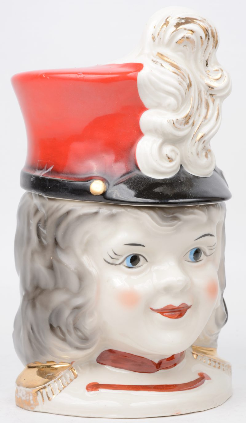 Een dekseldoos van meerkleurig porselein in de vorm van het hoofd van een majorette.