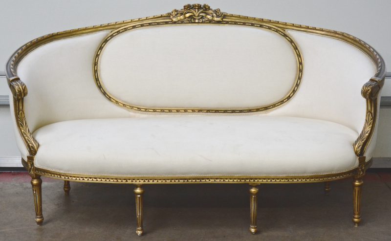 Een grote canapé van goudgepatineerd hout in Lodewijk XVI-stijl.