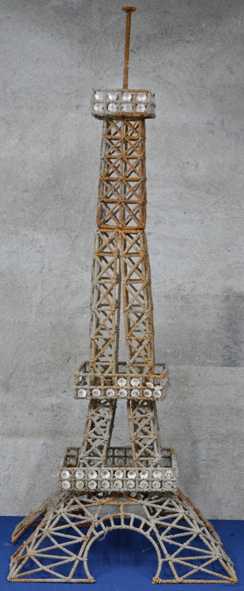 Een model van de Eiffeltoren, bestaande uit drie delen van metaaldraad en versierd met doorschijnende kraaltjes van kunststof.
