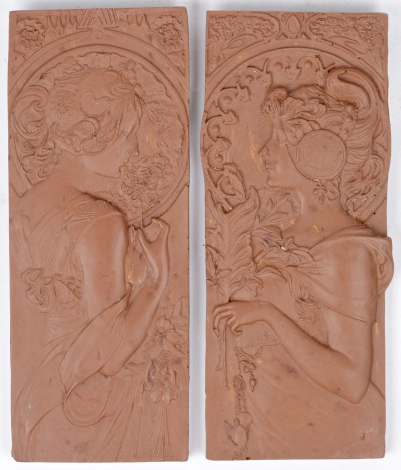 Een paar plaquettes van bruingepatineerd terracotta met reliëfdecors van jonge vrouwen in art nouveaustijl naar voorbeeld van Alfons Mucha.